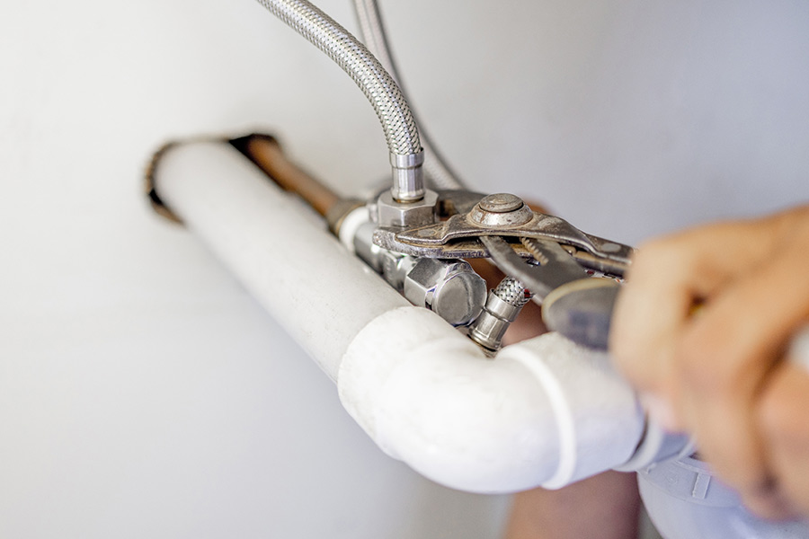 Plumber tightening a pipe connection with a wrench